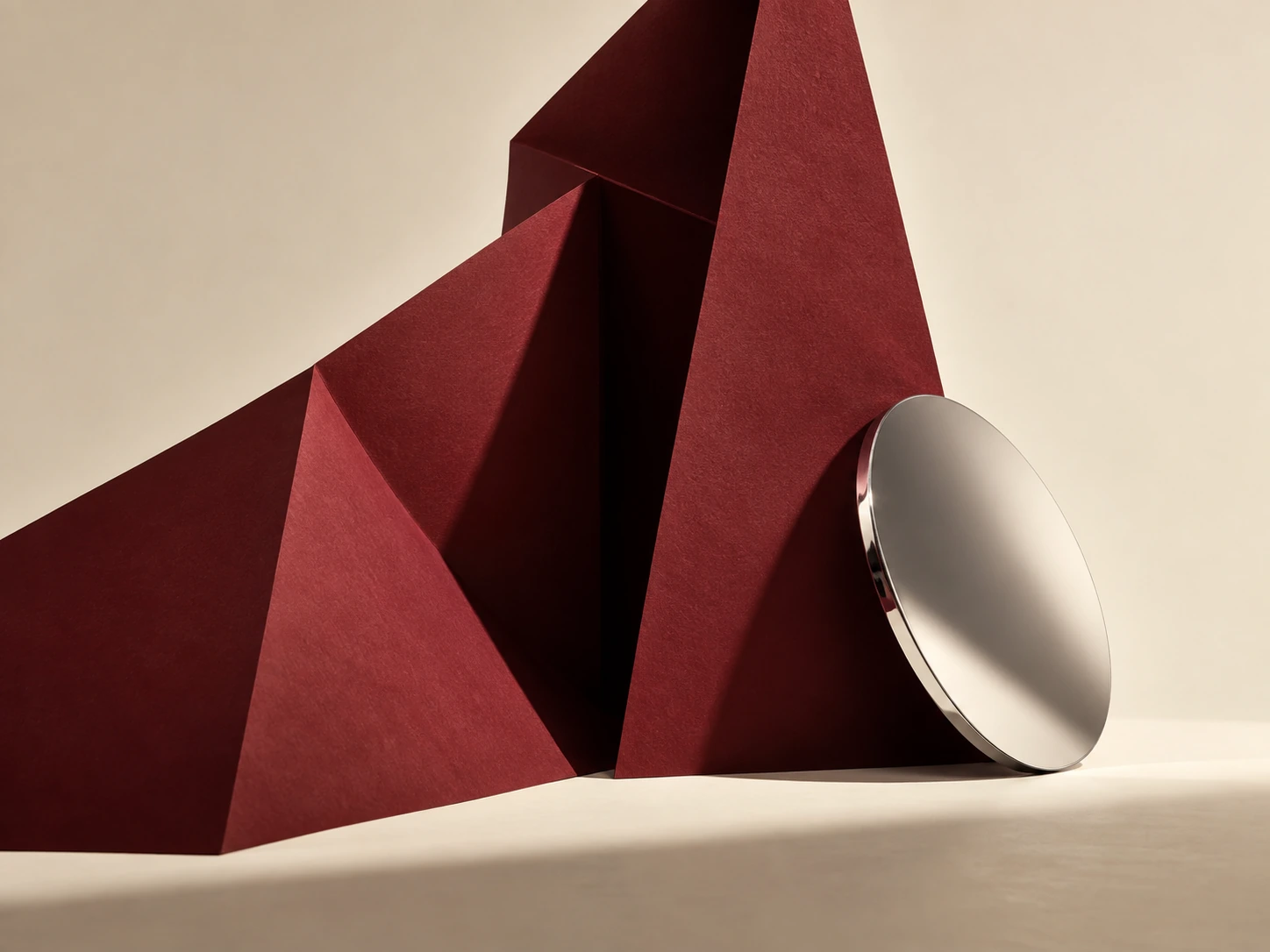Burgundy paper architecture with a polished chrome disc.